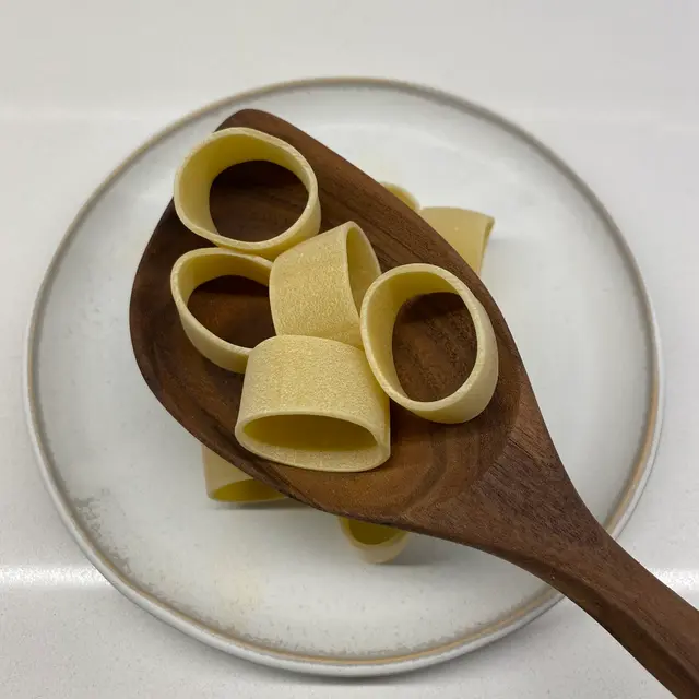 Calamarata in a wooden serving spoon