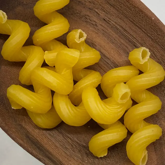 A close up shot of Cavatappi in a wooden serving spoon