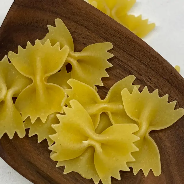 A close up shot of Farfalle in a wooden serving spoon