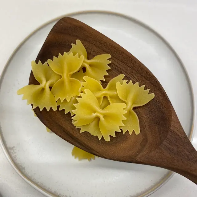 Farfalle in a wooden serving spoon