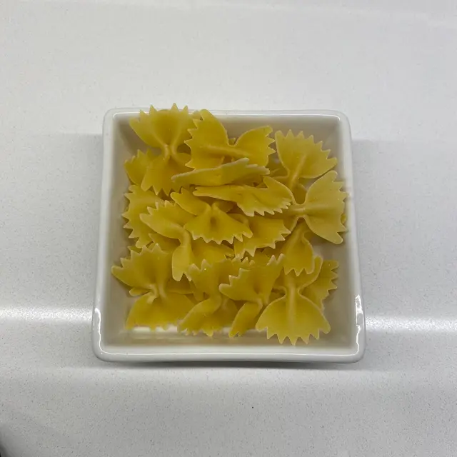 Farfalle in a square white glass bowl