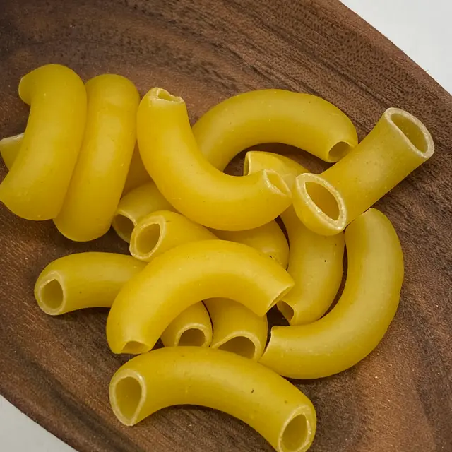 A close up shot of Large Elbow Macaroni in a wooden serving spoon