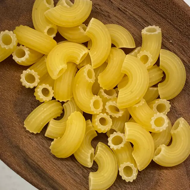 A close up shot of Small Elbow Macaroni in a wooden serving spoon