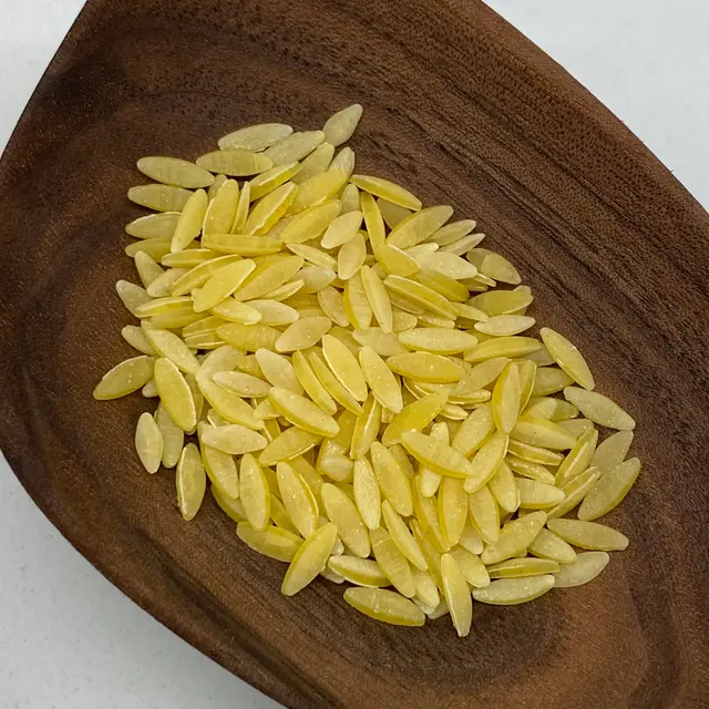 A close up shot of Orzo in a wooden serving spoon