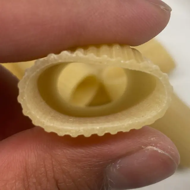 A close up shot of Paccheri held between fingers