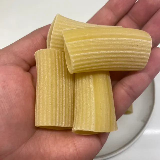 A close up shot of Paccheri in a hand