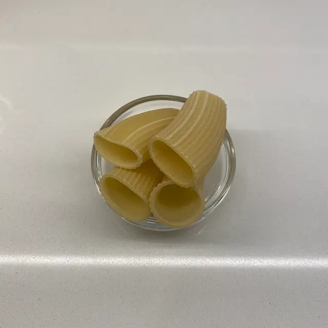 Paccheri in a small round white glass bowl