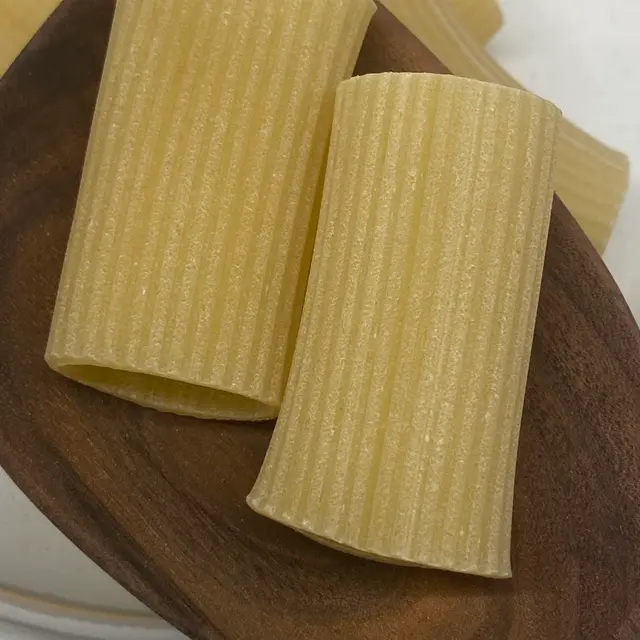 A close up shot of Paccheri in a wooden serving spoon