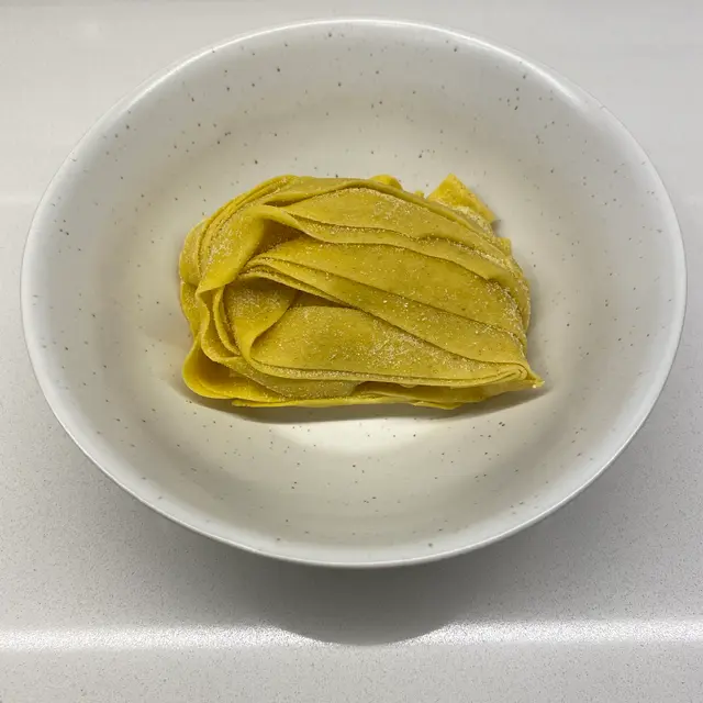 Pappardelle in a speckled white bowl