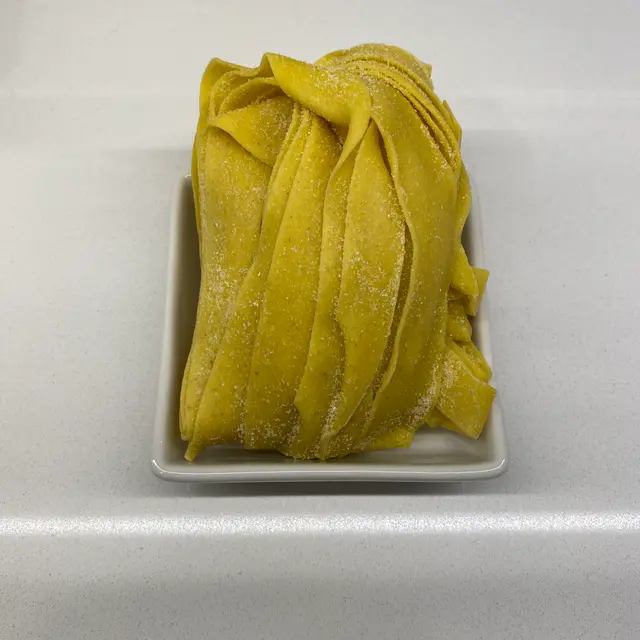 Pappardelle in a square white glass bowl