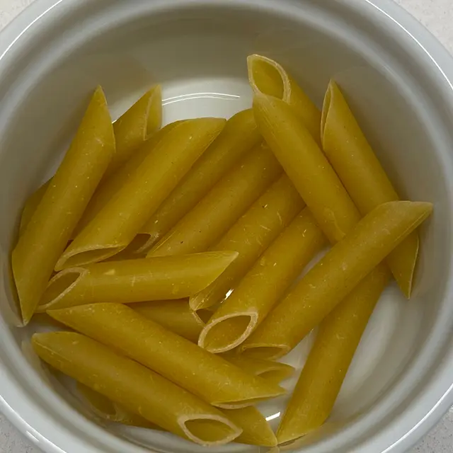 A close up shot of Penne in a round white ramekin