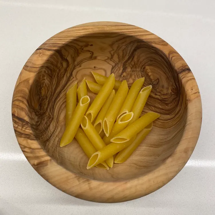 Penne in a round wooden bowl