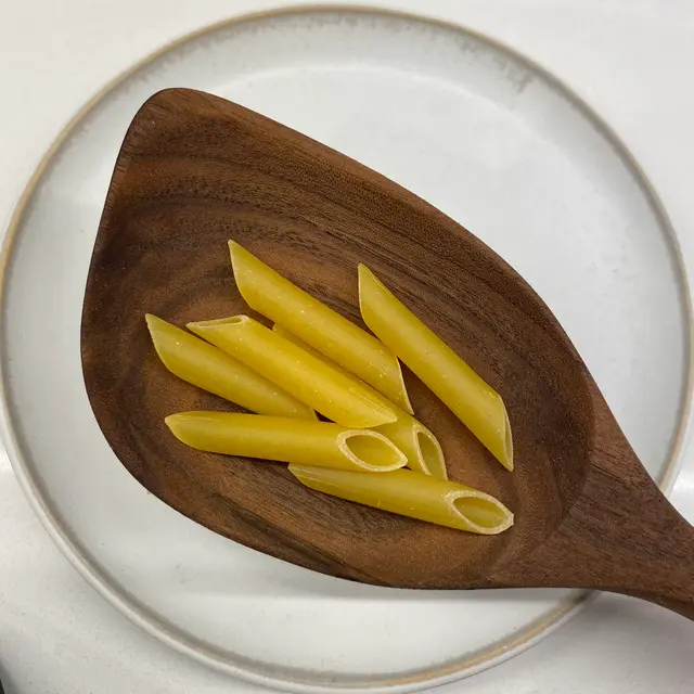 Penne in a wooden serving spoon