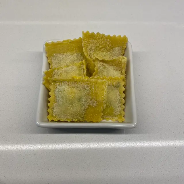 Ravioli in a square white glass bowl