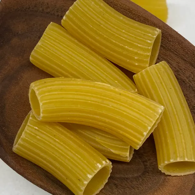 A close up shot of Rigatoni in a wooden serving spoon