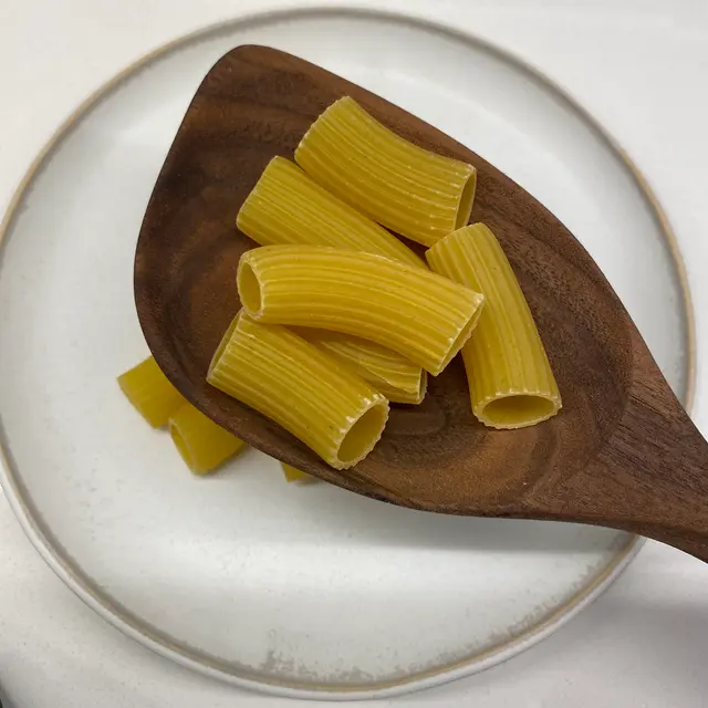 Rigatoni in a wooden serving spoon