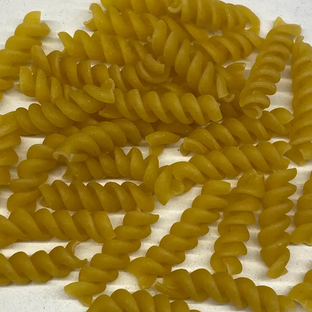 A close up shot of Rotini on a white kitchen counter