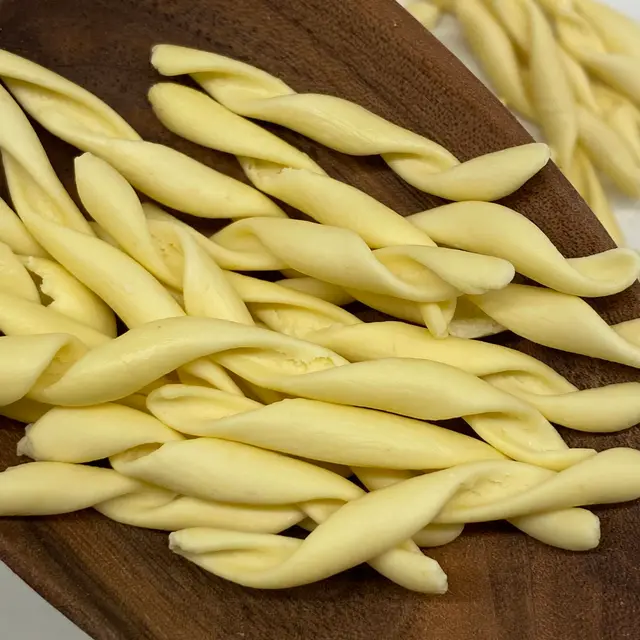 A close up shot of Strozzapreti in a wooden serving spoon