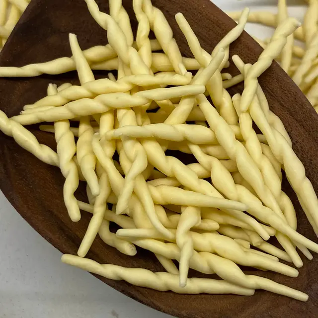 A close up shot of Trofie in a wooden serving spoon