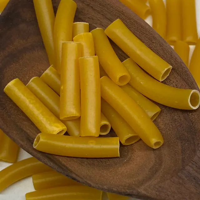 A close up shot of Ziti in a wooden serving spoon