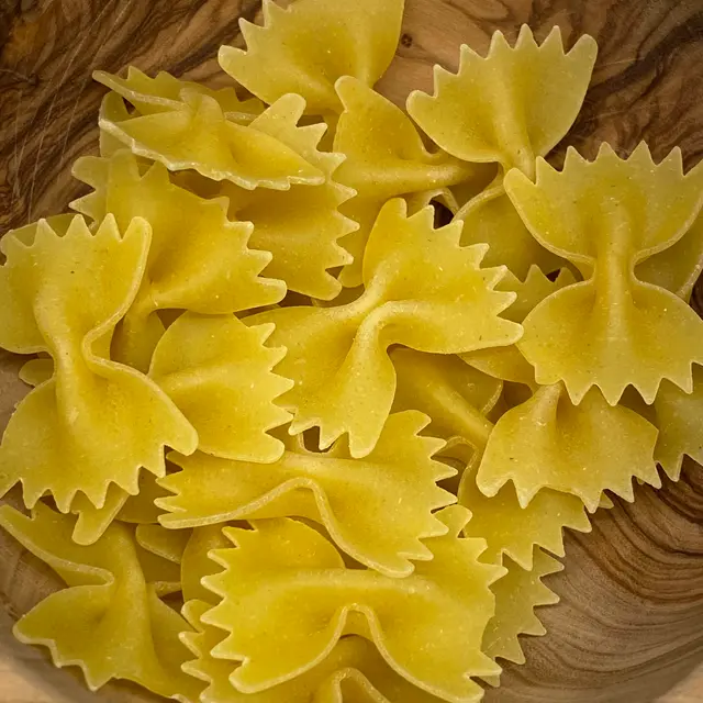 A close up shot of Farfalle in a round wooden bowl