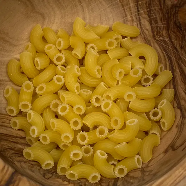 A close up shot of Small Elbow Macaroni in a round wooden bowl