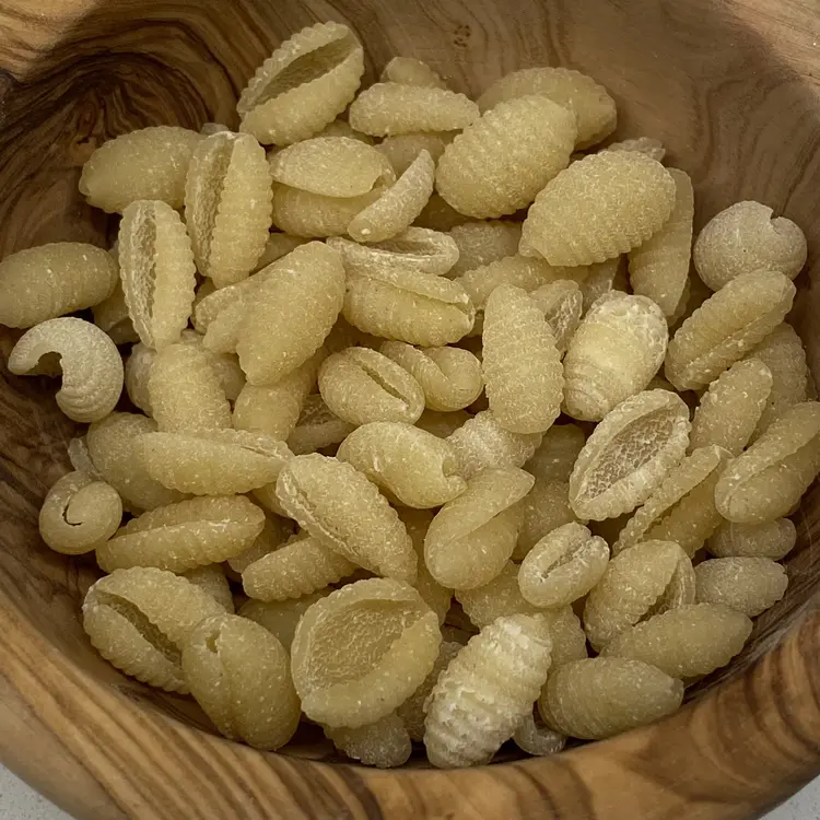 A close up shot of Malloreddus in a round wooden bowl