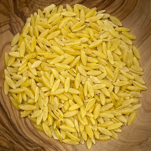A close up shot of Orzo in a round wooden bowl