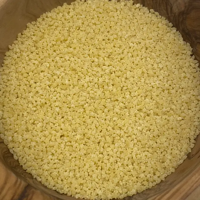 A close up shot of Pastina in a round wooden bowl