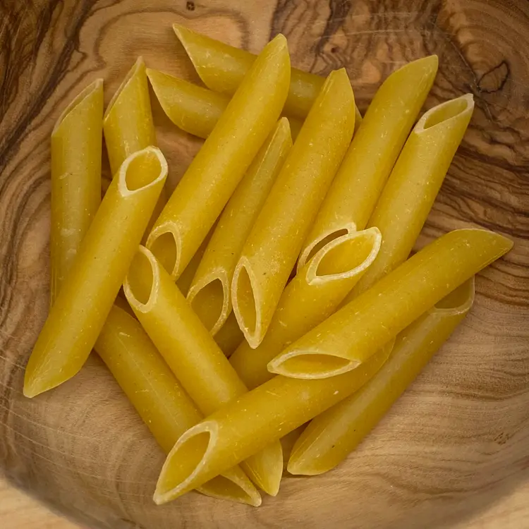 A close up shot of Penne in a round wooden bowl