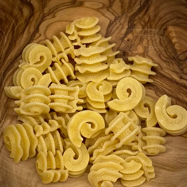 A close up shot of Radiatore in a round wooden bowl