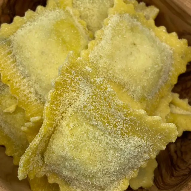 A close up shot of Ravioli in a round wooden bowl