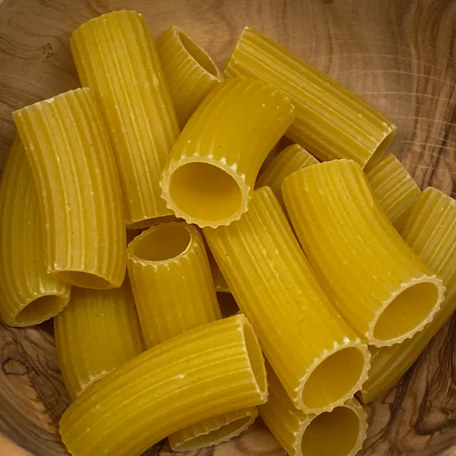 A close up shot of Rigatoni in a round wooden bowl
