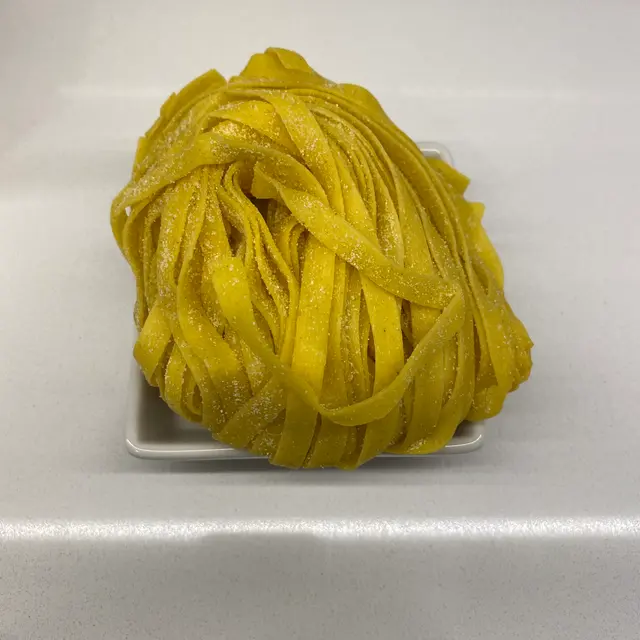 Tagliatelle in a square white glass bowl